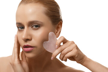 Beautiful young woman doing facial massage with gua sha tool on white background, closeup