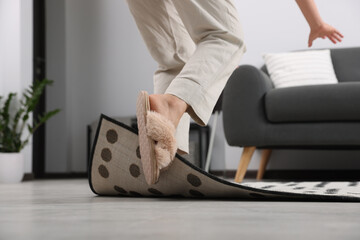Woman tripping over carpet at home, closeup