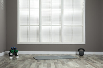 Mat with different dumbbells in spacious room