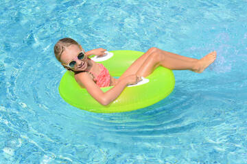 Cute little girl with inflatable ring in pool on sunny day