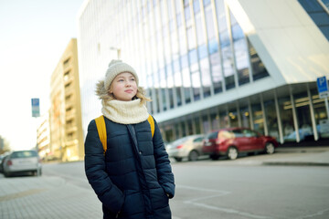 Cute young girl with a backpack heading to school on cold winter morning. Child going back to school.