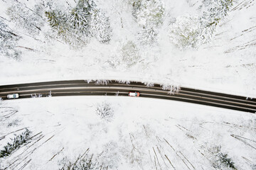 Beautiful aerial view of snow covered pine forests and a road winding among trees. Rime ice and hoar frost covering trees.