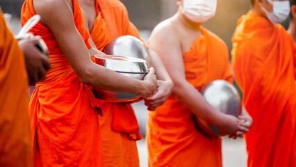 Buddhist monk holding alms bowl waitting for buddhism make merit by offering food and water at morning