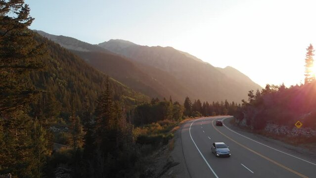 Road with cars in the Wasatch mountains, Little Cottonwood Canyon at sunset. Drone Video