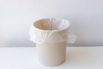 Empty trash container or bin with white plastic bag