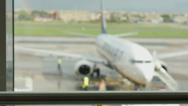 Blurred background 4K and window view with rain drops of airplane which is ready for departing on runway and seeing passengers and luggage for travelling shows concept of airline transportation.