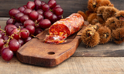 Close up chestnuts chorizo and grapes on rustic wooden table