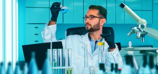 Chemist watching chemical process in flask. Scientist in gloves pouring blue acid into test tube...