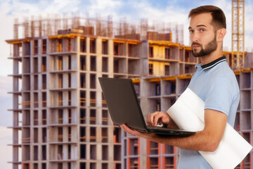 Engineer inspecting construction site. Builder with laptop on background of building under...
