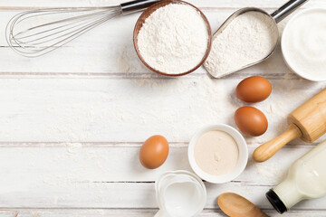 Fototapeta na wymiar Homemade dough recipe (eggs, flour, milk, sugar) and kneaded dough on a wooden table. view from above