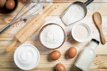 Fototapeta na wymiar Homemade dough recipe (eggs, flour, milk, sugar) and kneaded dough on a wooden table. view from above