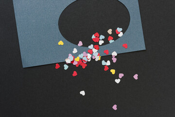 oval paper frame with heart confetti on black paper