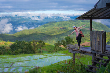 Beautiful Asian tourism women on the balcony of the cottage and lush green rice paddy fields are flooded parcels.