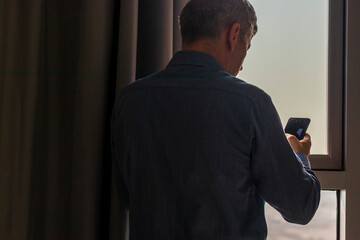 Silhouette of a man with mobile phone at the window. Concept