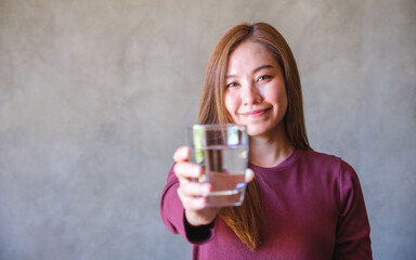 Portrait image of a young woman holding and giving a glass of water