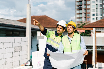 Engineering and Contractor in vest with wear safety hardhat hold a blueprint and talk about...