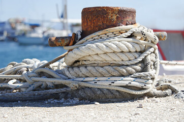 Rostiger Poller am Hafen mit mehreren Tampen Seilen behangen in der Seitansicht, horizontal 