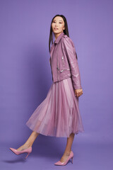 Fashion asian female model. Lilac leather jacket, lilac skirt, heels, sunglasses.