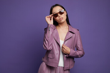 Fashion asian female model. Lilac leather jacket, lilac skirt