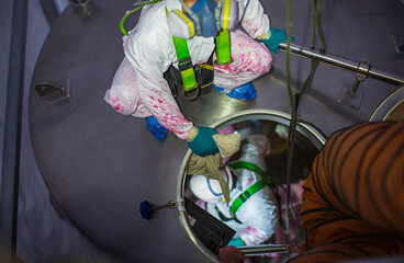 Top view male climbs up the stairs into the tank stainless chemical area confined space safety