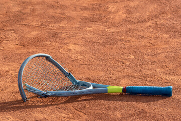 Broken tennis racket on clay tennis court. Mental health problem in sports. Negative emotions, stress, dissatisfaction, defeat, crash, failure, loss concept