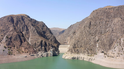 Fototapeta na wymiar Beautiful rocky mountains in Kyrgyzstan. Aerial view of the dam at the green-blue mountain lake.