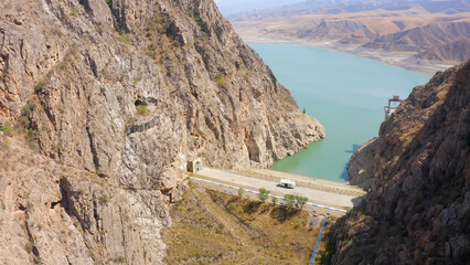 Aerial view of the dam at the mountain reservoir. Rocky mountains, hills and slopes of Kyrgyzstan