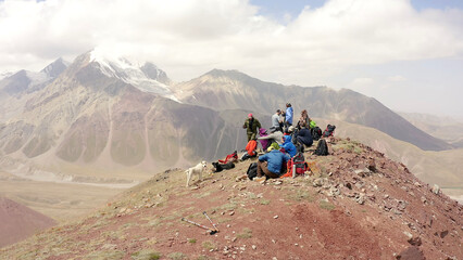 Fototapeta premium A group of climbers with a dog are resting on the top of the Red Katya Mountain. Beautiful summer mountain landscape.