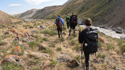 A group of tourists with backpacks walking in the Pamir mountains . Beautiful summer mountain...