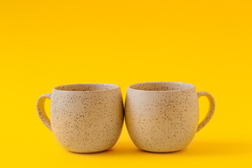 Two empty ceramic cups on a yellow background, copy space