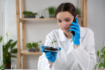 Scientist Talking on Phone in Agronomy Laboratory with young plants. Analysis of growing GMO - Powered by Adobe