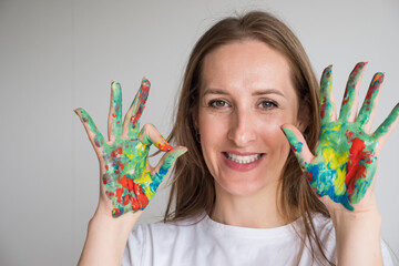 Mature woman with painted hands shows OK sign. Brown-haired model enjoys capturing innocent moments smiling in studio. Lady looks with happy expression - obrazy, fototapety, plakaty