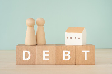 DEBTと書かれたブロックと家と人形
