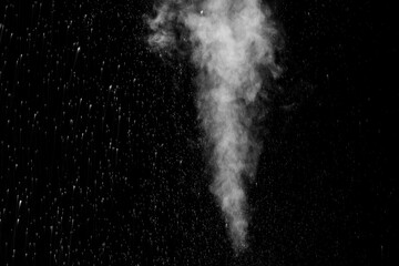 Curly white steam rising up and splashing water scattering in different directions isolated on a black background