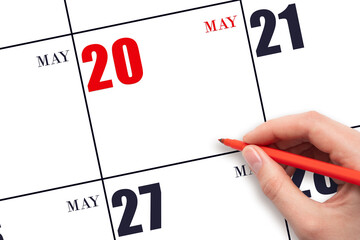 A hand holding a red pen and pointing on the calendar date May 20. Red calendar date, copy space,...