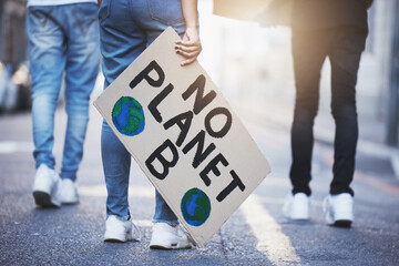 People with climate change poster or banner protest on asphalt road, street or city. Legs of group...