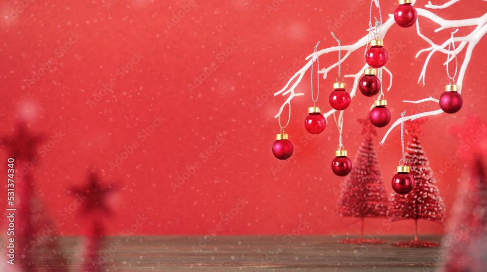 Poster merry christmas with xmas tree and bauble ball at vivid red wall at wooden table.copy space for addi