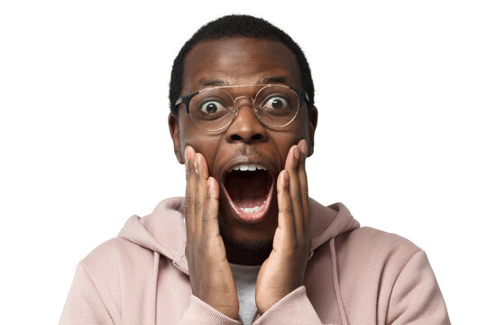 Closeup shot of young handsome African guy in casual clothes pictured wearing round spectacles, looking extremely surprised with round eyes and mouth, positively shocked