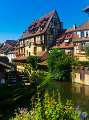 Fototapeta na wymiar View of Little Venice, picturesque blooming old tourist area in historic center of Colmar city along canals of Lauch river on summer day, France