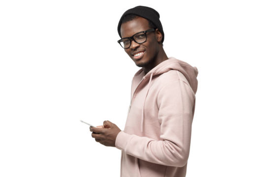 Black guy looking and smiling at the camera with cheerful expression while texting his friends, using mobile phone