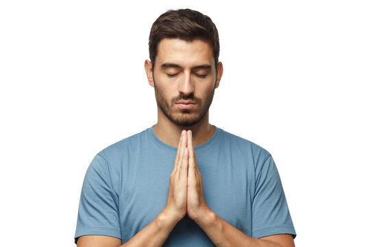 Closeup of young man putting hands together as if he is praying with closed eyes