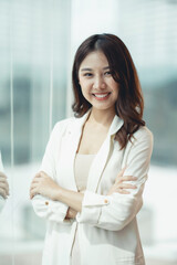 Beautiful and confident Asian businesswoman standing with her arms crossed and smiling brightly at the camera in the office.