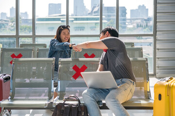 smiling friends fist bumb at departure seat in airport terminal