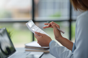 Close-up of the hand of a business woman using a calculator to check financial statement, balance...