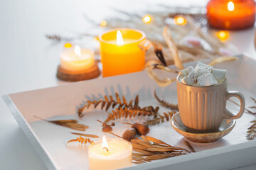 two cups of  coffee  with marshmallows  and autumn decor on white wooden tray