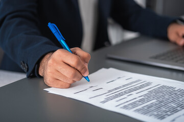 West eastern businessman hand sign a contract on the desk, closeup
