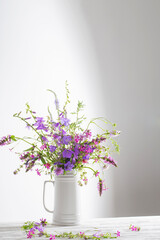 Fototapeta premium summer wild flowers in white jug on white background