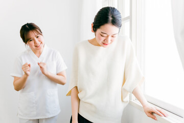 Fototapeta premium リハビリ治療で痛みに耐える女性と笑顔の看護師（理学療法士・作業療法士） 