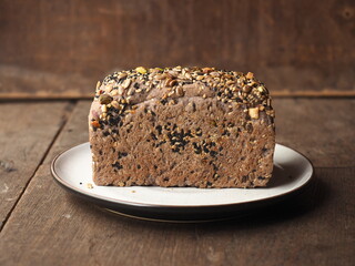 loaf of cereal crusted rice berry bread on plate on wooden background