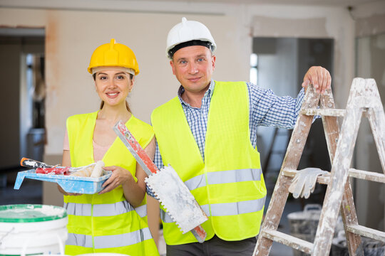 Portrait of young woman and adult man interior construction workers engaged in building improvement and renovation